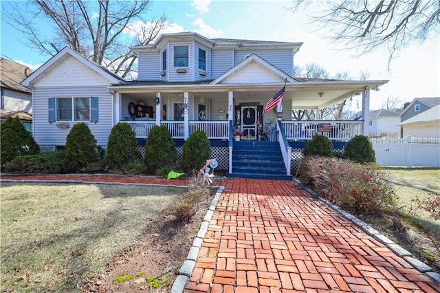 view of front of house with a porch, fence, and a front yard