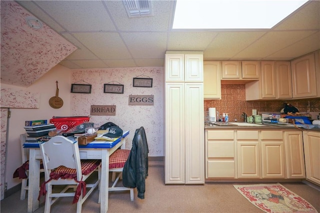 kitchen featuring visible vents, wallpapered walls, baseboards, a drop ceiling, and a sink