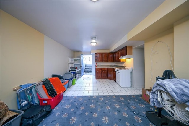 kitchen with light tile patterned floors, visible vents, white range with gas stovetop, light countertops, and under cabinet range hood