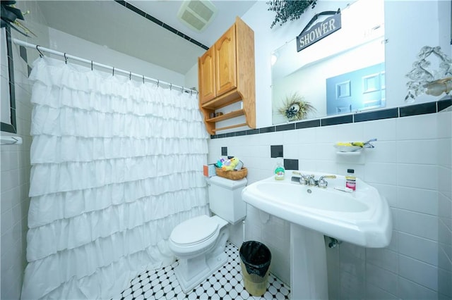 full bath featuring tile patterned flooring, visible vents, toilet, a shower with curtain, and tile walls