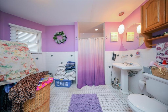 full bathroom with a shower with curtain, tile walls, toilet, and a wainscoted wall