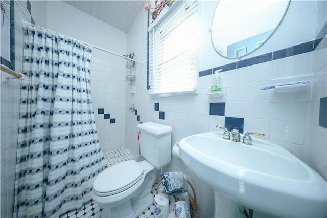 full bathroom with tile walls, toilet, a tile shower, and a sink