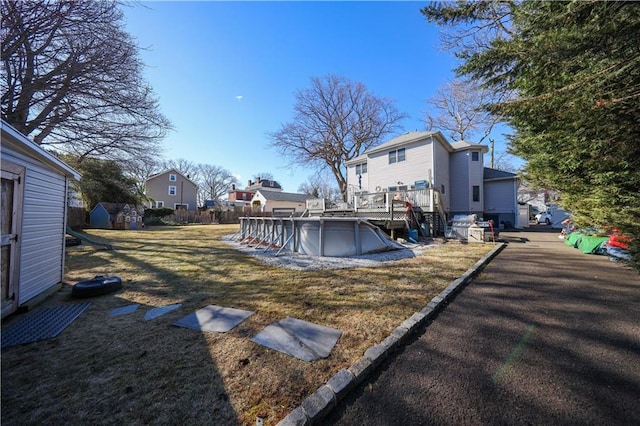 view of yard with an outbuilding, a deck, a residential view, a storage shed, and an outdoor pool