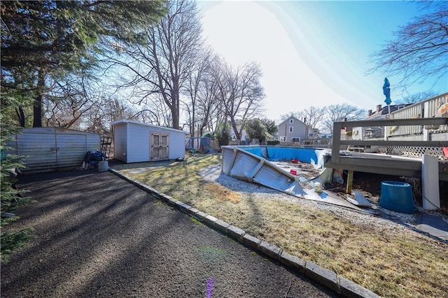 view of yard featuring an outdoor pool, a storage unit, and an outdoor structure