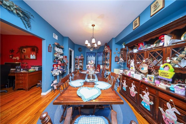 dining space with a notable chandelier, wood finished floors, visible vents, and baseboards