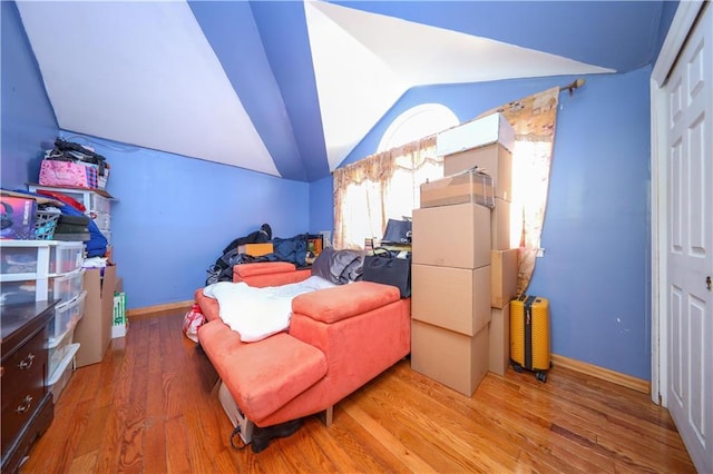bedroom with vaulted ceiling, wood finished floors, and baseboards