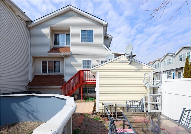 rear view of house featuring stairway and fence