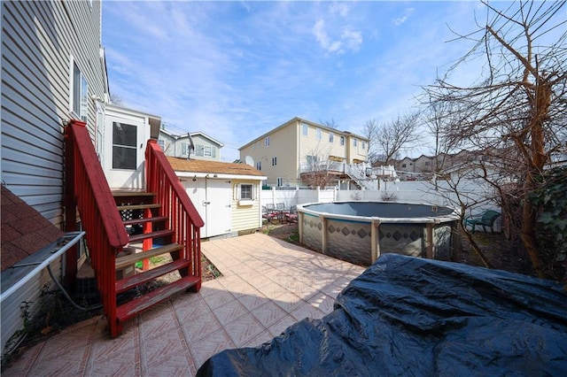view of patio / terrace featuring a fenced backyard, a fenced in pool, entry steps, a residential view, and a shed