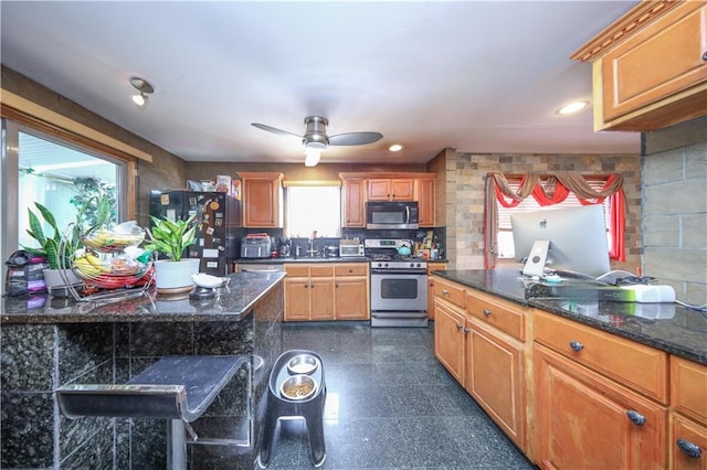 kitchen with recessed lighting, dark stone counters, granite finish floor, appliances with stainless steel finishes, and a ceiling fan