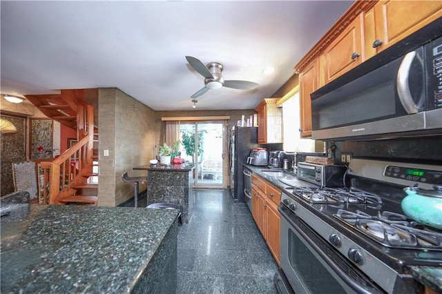 kitchen with granite finish floor, ceiling fan, stainless steel gas range, dishwashing machine, and brown cabinetry