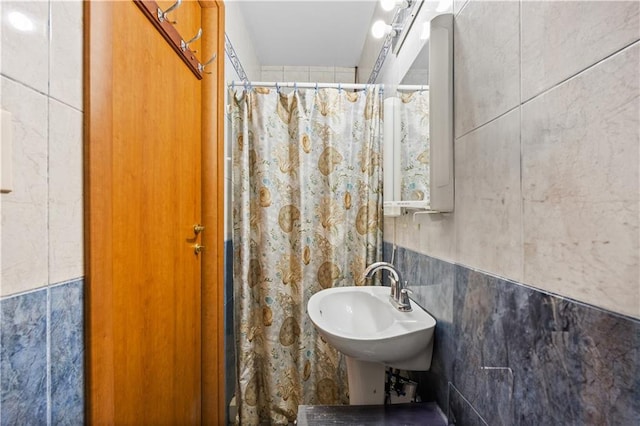 full bathroom with a shower with shower curtain, tile walls, and a sink