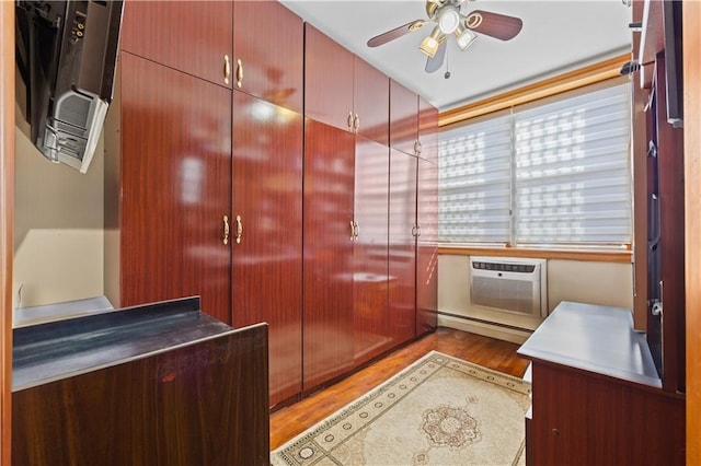 interior space featuring baseboard heating, an AC wall unit, wood finished floors, and a ceiling fan