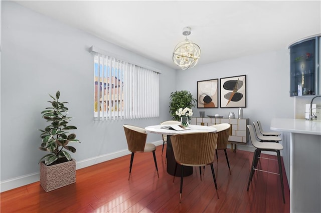 dining space featuring a chandelier, baseboards, and wood finished floors