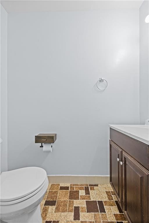 bathroom with baseboards, toilet, and vanity