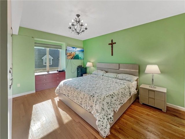 bedroom with baseboards, an inviting chandelier, and wood finished floors