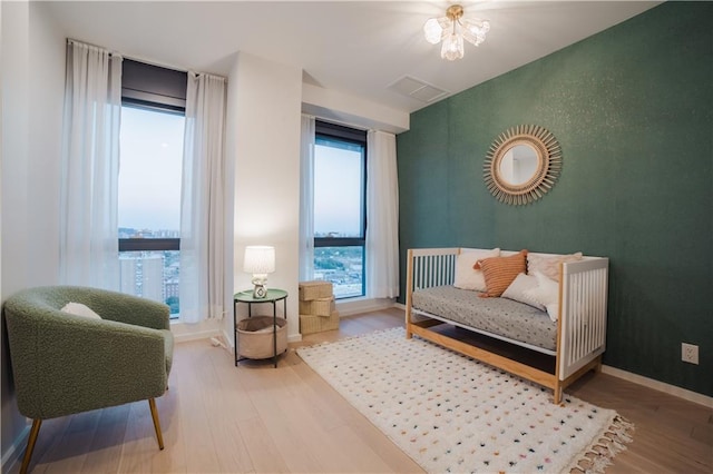 sitting room featuring an accent wall, visible vents, wood finished floors, and baseboards