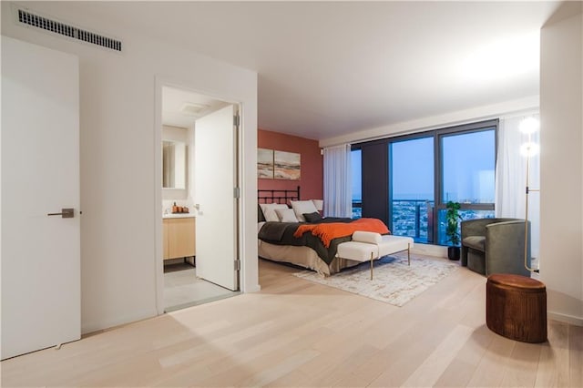 bedroom featuring ensuite bathroom, visible vents, and light wood finished floors