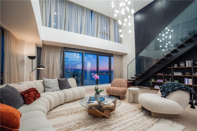 living room with stairs, wood finished floors, a towering ceiling, and a chandelier