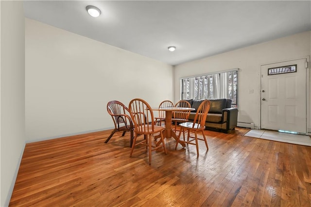 dining space with a baseboard heating unit, baseboards, and wood-type flooring