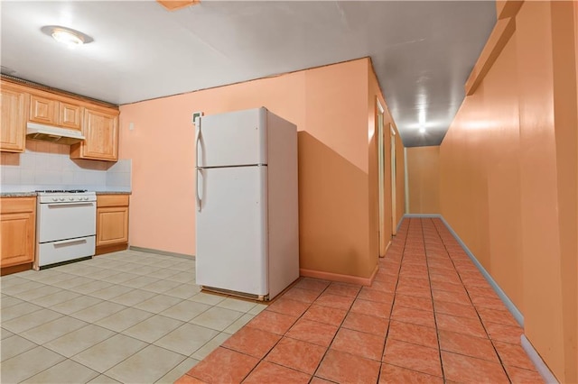 kitchen featuring under cabinet range hood, light countertops, light tile patterned floors, decorative backsplash, and white appliances