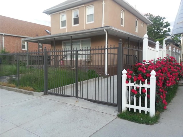 view of gate featuring covered porch and a fenced front yard