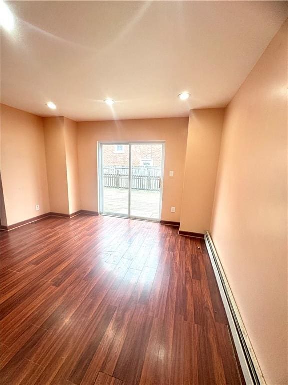 spare room with recessed lighting, baseboards, baseboard heating, and dark wood-style floors