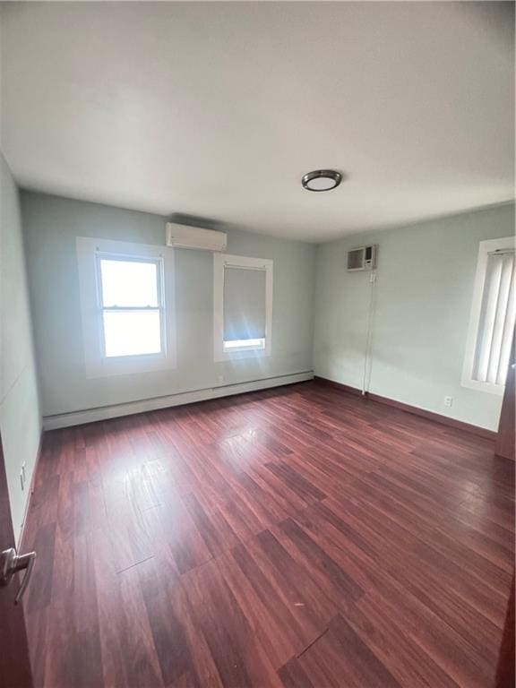 spare room with a baseboard heating unit, a wall unit AC, dark wood-style floors, and a wall mounted air conditioner