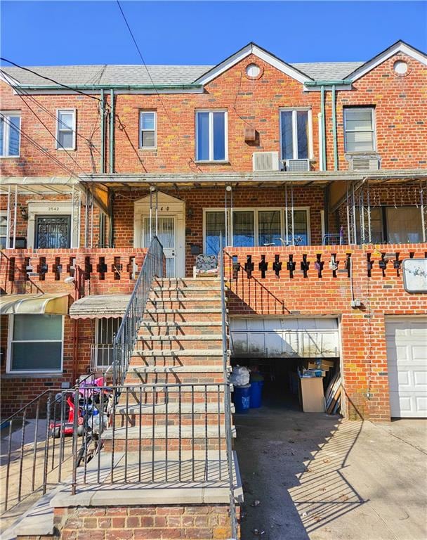 view of front of home with brick siding, a garage, stairs, and driveway