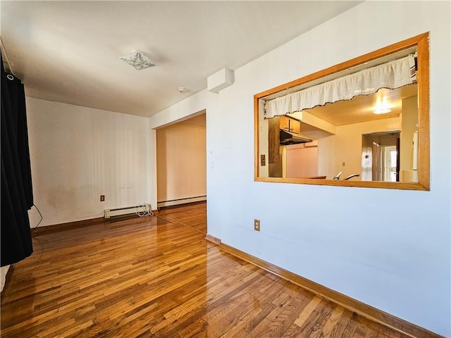 empty room featuring baseboards, a baseboard radiator, and wood finished floors