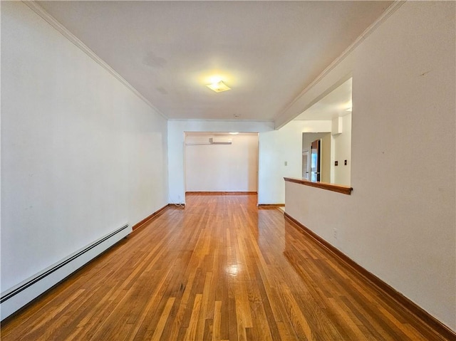 empty room featuring baseboards, ornamental molding, a baseboard heating unit, and hardwood / wood-style flooring