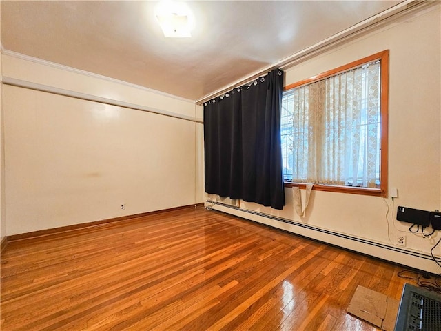 spare room with ornamental molding, a baseboard heating unit, and hardwood / wood-style floors
