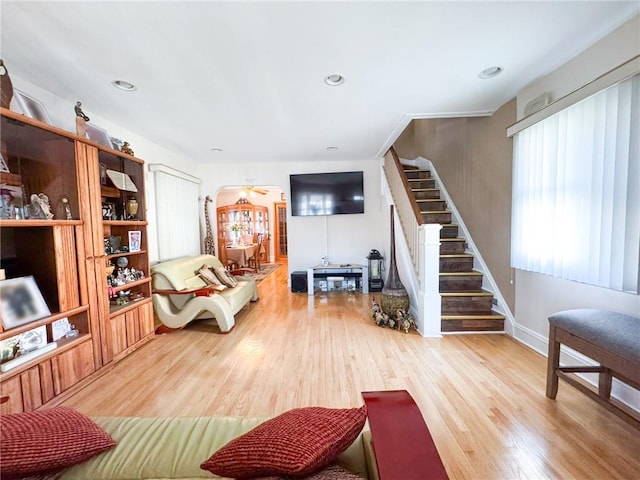 living room featuring recessed lighting, arched walkways, wood finished floors, and stairs