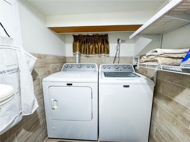 laundry area with laundry area, tile walls, and independent washer and dryer