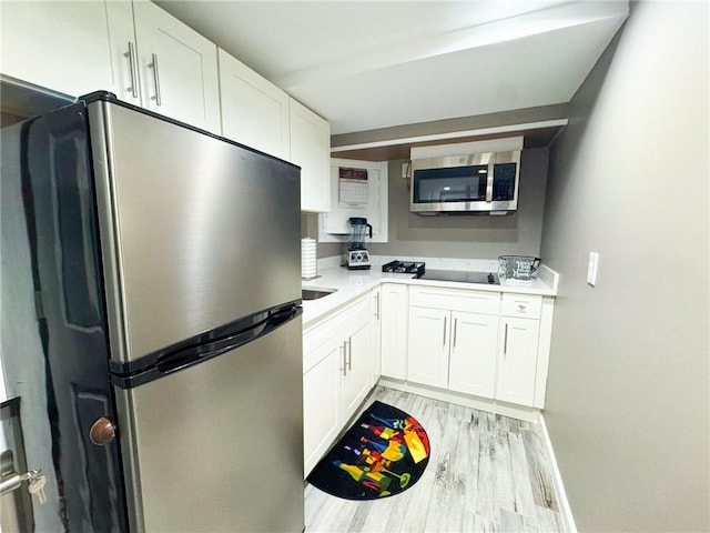 kitchen featuring baseboards, light wood-style flooring, light countertops, appliances with stainless steel finishes, and white cabinetry