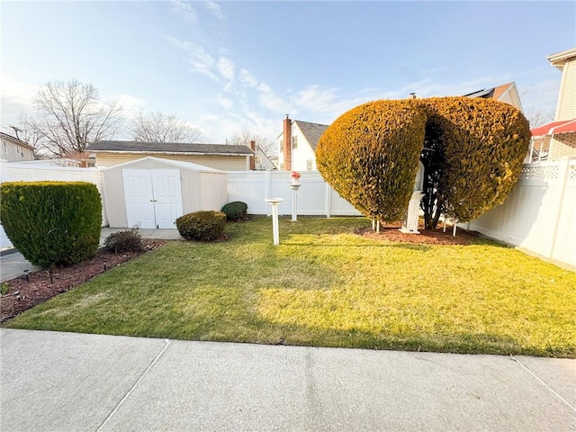 view of yard with a storage shed, a fenced backyard, and an outdoor structure