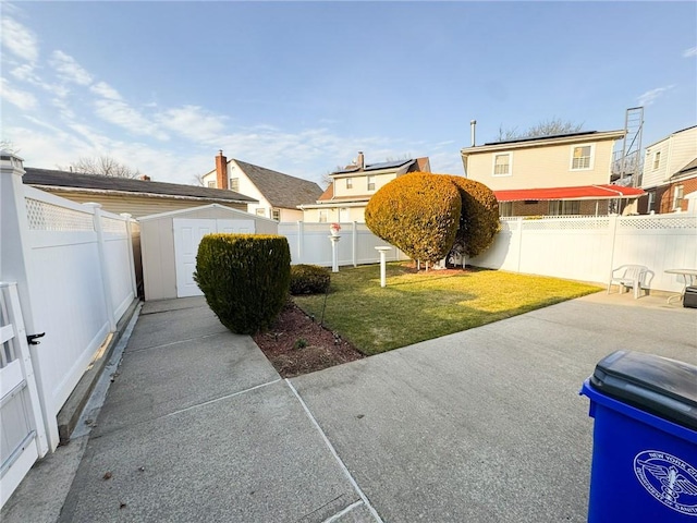 view of yard featuring a patio area, a storage unit, a fenced backyard, and an outdoor structure