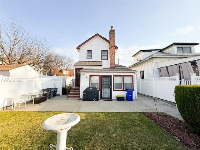 back of house featuring a fenced backyard, a lawn, and a chimney