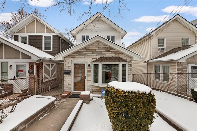 snow covered property featuring stone siding and fence