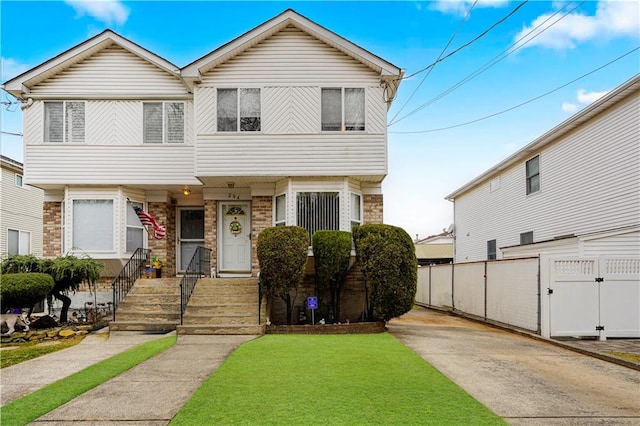 multi unit property featuring a gate, a front lawn, and fence