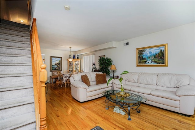 living room featuring stairway, visible vents, and light wood-type flooring