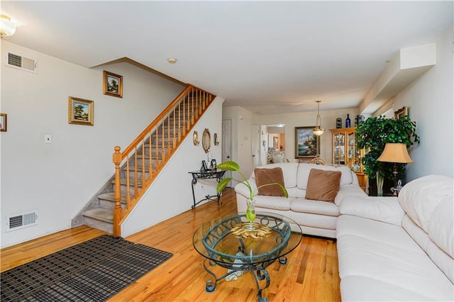 living room featuring visible vents, wood finished floors, and stairs