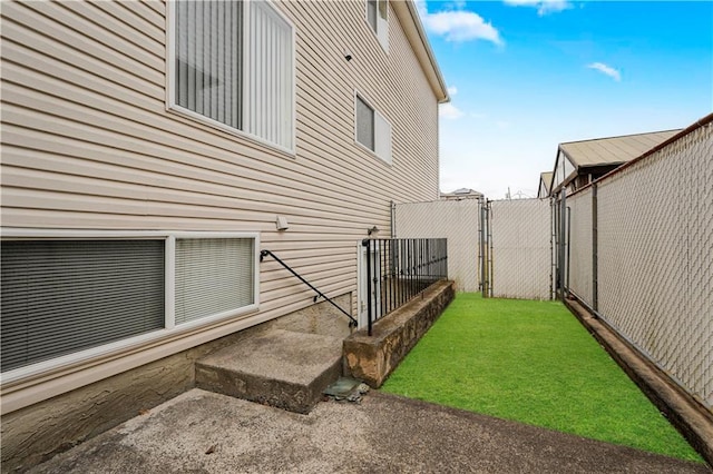 view of side of property featuring fence, a yard, and a gate