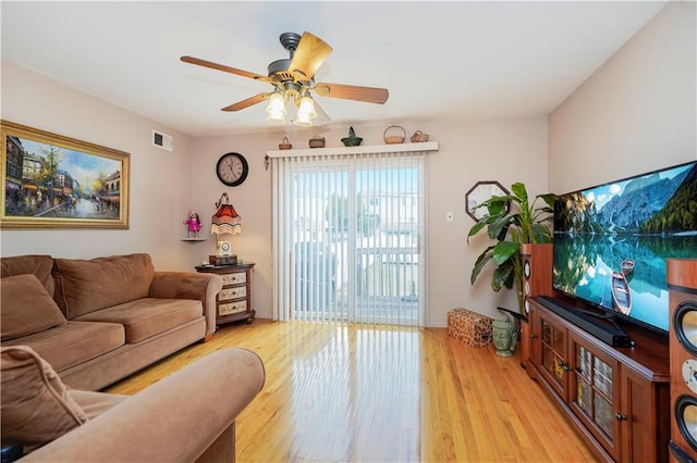 living room with light wood-style floors, visible vents, and ceiling fan