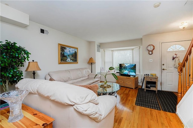 living room with visible vents, stairs, and light wood-style floors