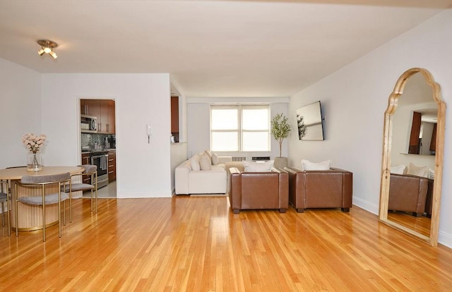 living area featuring baseboards and light wood finished floors