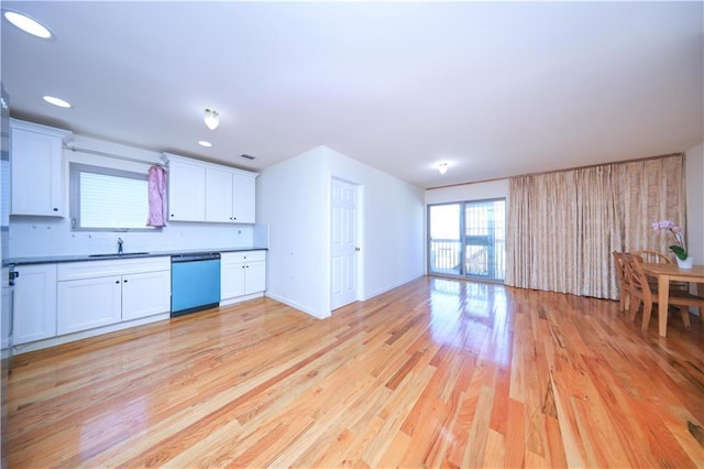 kitchen featuring dark countertops, open floor plan, white cabinets, light wood finished floors, and dishwashing machine