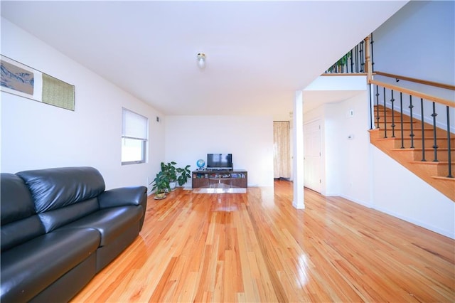 living room featuring hardwood / wood-style flooring, stairway, and baseboards