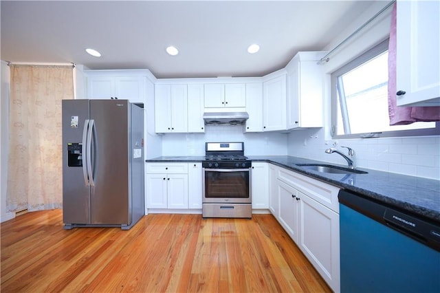 kitchen with under cabinet range hood, white cabinets, appliances with stainless steel finishes, and a sink