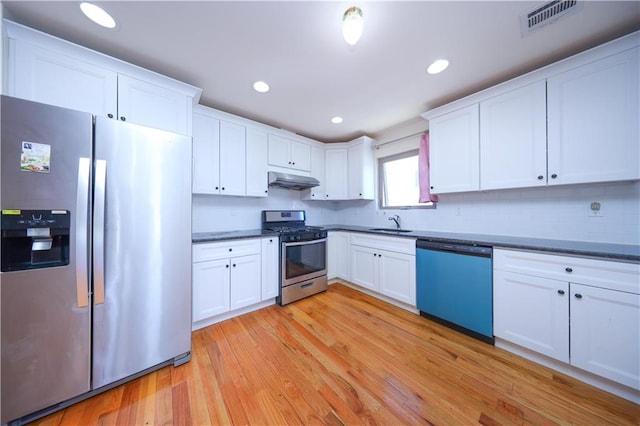 kitchen featuring dark countertops, visible vents, under cabinet range hood, appliances with stainless steel finishes, and light wood-style floors