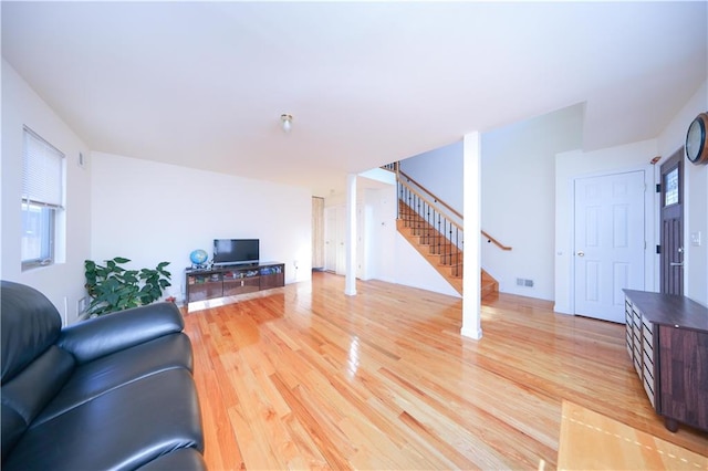 living area with stairs, light wood-style floors, and visible vents